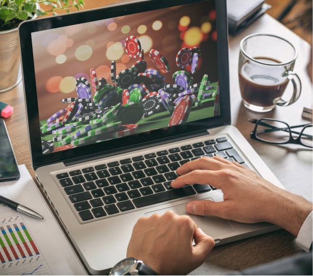 Una persona juega en los mejores casinos online desde su ordenador portátil MacBook Pro de Apple, con una taza de café a su lado